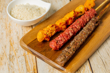 espetinho, brazilian skewer with meat. chicken, sausage and meat over wooden table