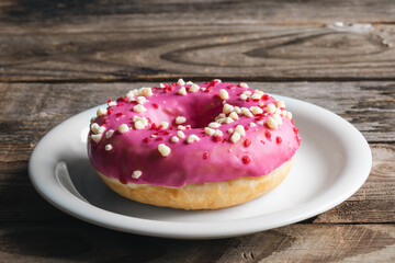 Close-up, appetizing pink donut on a wooden background.