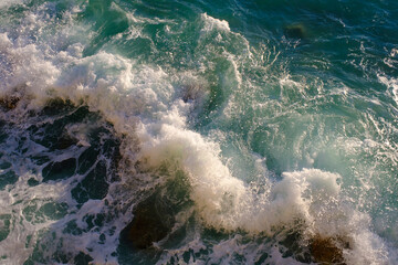 Rock breaking with sea water, outdoors, waves and rocks, splash and foam, top view.