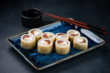 Set of Japanese sushi rolls with salmon, cream cheese, tamago omelet, sesame seeds and soy sauce.