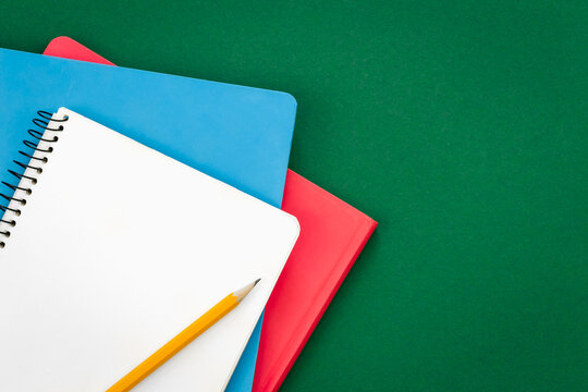Notebooks on green background, school concept, flat lay.