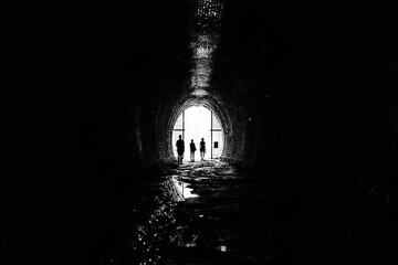 Silhouetted people standing at the entrance of Oxendon tunnels, Northamptonshire, UK; Northamptonshire, England