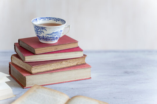 Teacup on pile of vintage books.