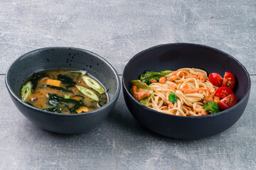 Asian lunch udon noodles with fish salmon and soup with tofu, seaweed, onions and shiitake mushrooms.