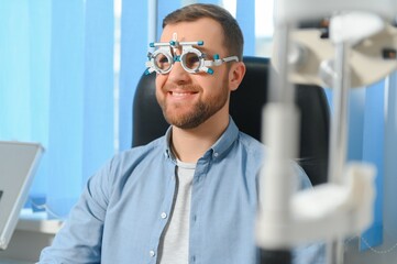 Handsome young man is checking the eye vision in modern ophthalmology clinic. Patient in...