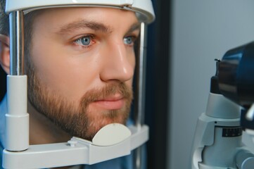 Adult man eyesight test with binocular slit-lamp. Checking retina of a male eye close-up....