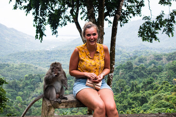 Tropical monkey eating with woman on a bench in the jungle © Sjors