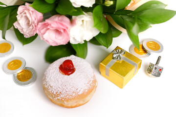 Image of Jewish holiday Hanukkah with donuts, wooden dreidels (spinning top), chocolate coins, flowers and gift wrappings
