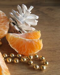 Tangerine slices on a wooden table near golden beads