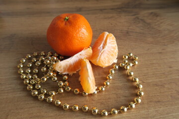 Tangerine slices on a wooden table near golden beads