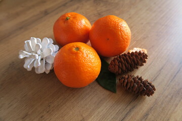 Tangerines next to cones on a wooden table