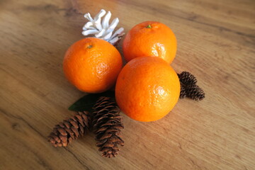 Tangerines next to cones on a wooden table