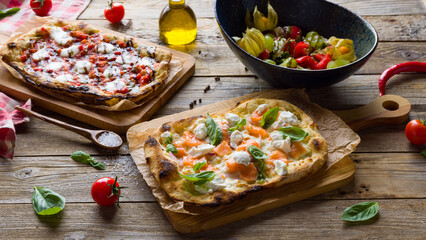 Pizza with salmon and cheese, pizza mozarella buffalo, vegetable salad on Roman dough, pinsa on wooden table