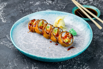 fried tempura shrimps roll with avocado and sauce on grey table