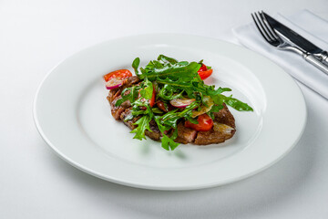 juicy Ribeye steak with tomatoes and aragula on white plate sliced