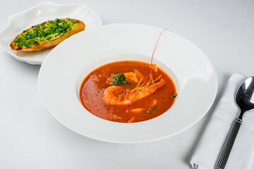 Tomato soup with squid and shrimps on white plate