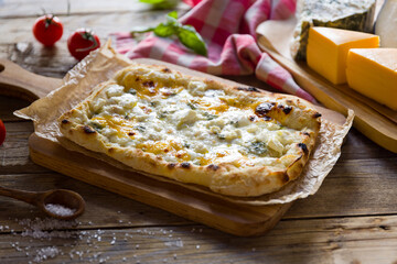 Roman pizza four cheeses on Roman dough, pinsa on wooden table