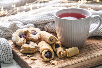 A cup of red tea and cookies on a blurred background with a knitted element.
