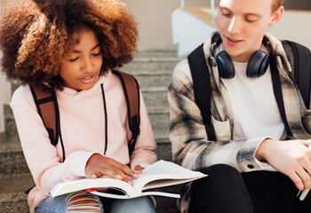 Girl and boy sitting together on a stairs preparing home assignments © Artem Varnitsin