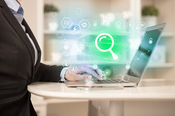 Hands working on laptop with digital icons