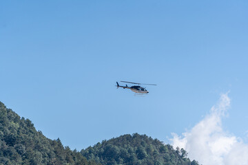 The helicopter flies over the mountains.