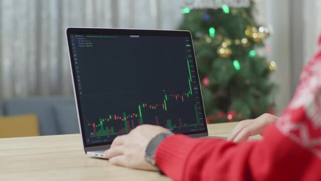 Close Up Of A Laptop Showing Profit Made On Stock Market While A Male Raising Hand For Celebrating On Christmas Day At Home
