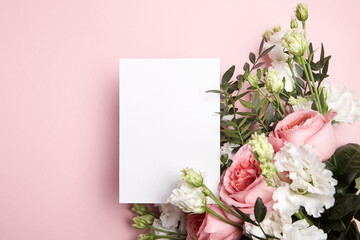 Obraz na płótnie Canvas Holiday greeting card mockup with flowers on light pink background, top view, flat lay. White wedding invitation mockup and floral decor