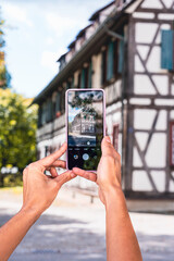 Naklejka premium phone in the hands of a girl photographing an old house