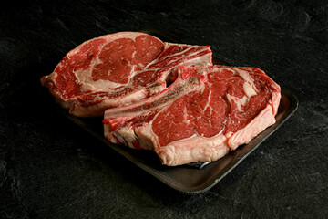 Thick bone in rib steak on a grocery store styrofoam tray.