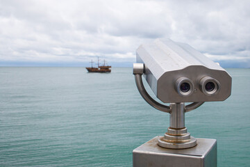 paid observation point for the sea through binoculars, against a blurred background of the sea and a distant ship and sailboat