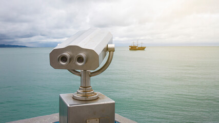 paid observation point for the sea through binoculars, against a blurred background of the sea and a distant ship and sailboat