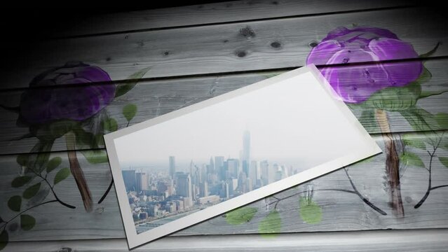 Animation of modern cityscape in white frame and purple flowers on wooden table