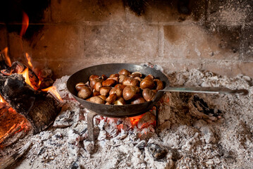 frying pan with grilled chestnuts, open fireplace