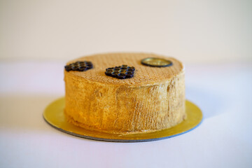 A slice of Russian Ukrainian Georgian honey cake with the whole cake in the background with a chocolate flourish on the top