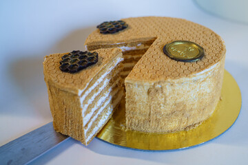 A slice of Russian Ukrainian Georgian honey cake with the whole cake in the background with a chocolate flourish on the top