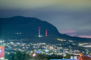 Large communication towers high in the mountains at night. The beautiful city Tuxtla Gutiérrez in Mexico.