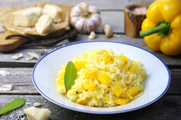 Italian food. Plate of yellow bell pepper risotto and grated parmesan cheese