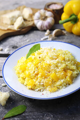Italian food. Plate of yellow bell pepper risotto and grated parmesan cheese