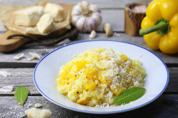 Italian food. Plate of yellow bell pepper risotto and grated parmesan cheese