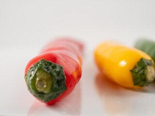 Red yellow and green chili peppers on a white background.
