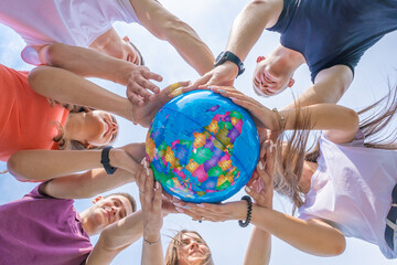 The concept of saving the world. A group of friends hold the world globe in their hands.