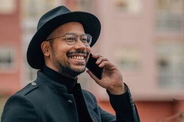 smiling latin man talking on mobile phone in the street