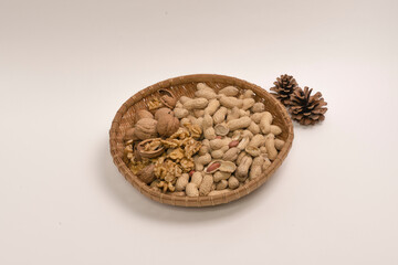 껍질이 있는 호두, 땅콩, 밤, 은행. 나무 접시에 담겨 있는. 흰배경. 한국의 1월 전통, 정월 대보름 부럼. 음력 달력.