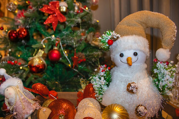 Snow man toy and other New Year's decorations, Christmas tree in the background