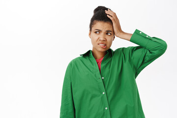 Portrait of concerned Black girl, holds hand on head complicated, confused and puzzled by smth,...