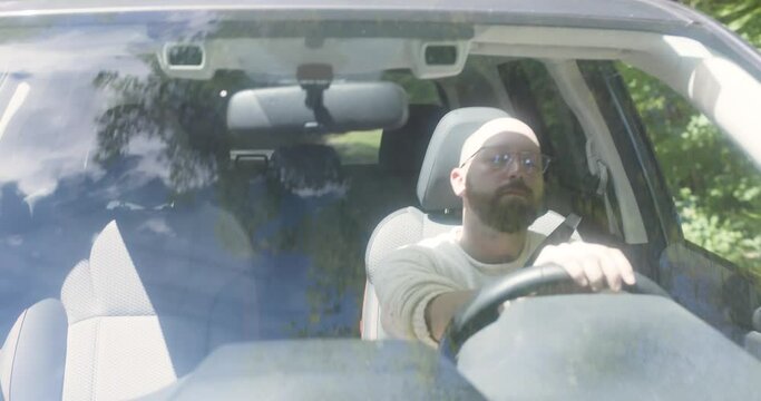 Bearded man drives on a bumpy dirt road through a thickly wooded area
