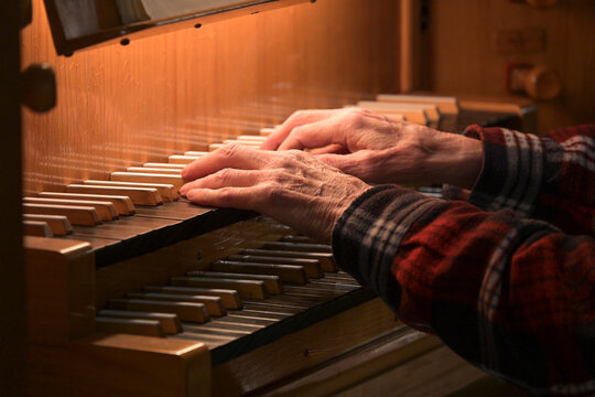 Old Hands of an organist playing on the organ keyboard also called manual, traditional musical instrument in the church, copy space, selected focus