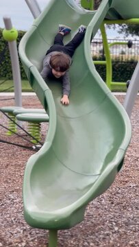 child playing on playground on a slide vertical 