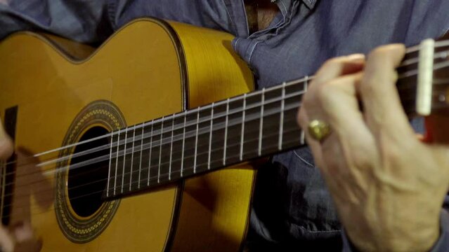 flamenco guitar played by a guitarist in detail where we see the hands move with impetus and speed and the guitar of yellow and brown colors shine and show off a pure art like flamenco music Spanish