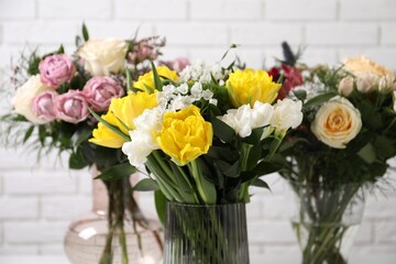Beautiful bouquets with fresh flowers against white brick wall, closeup